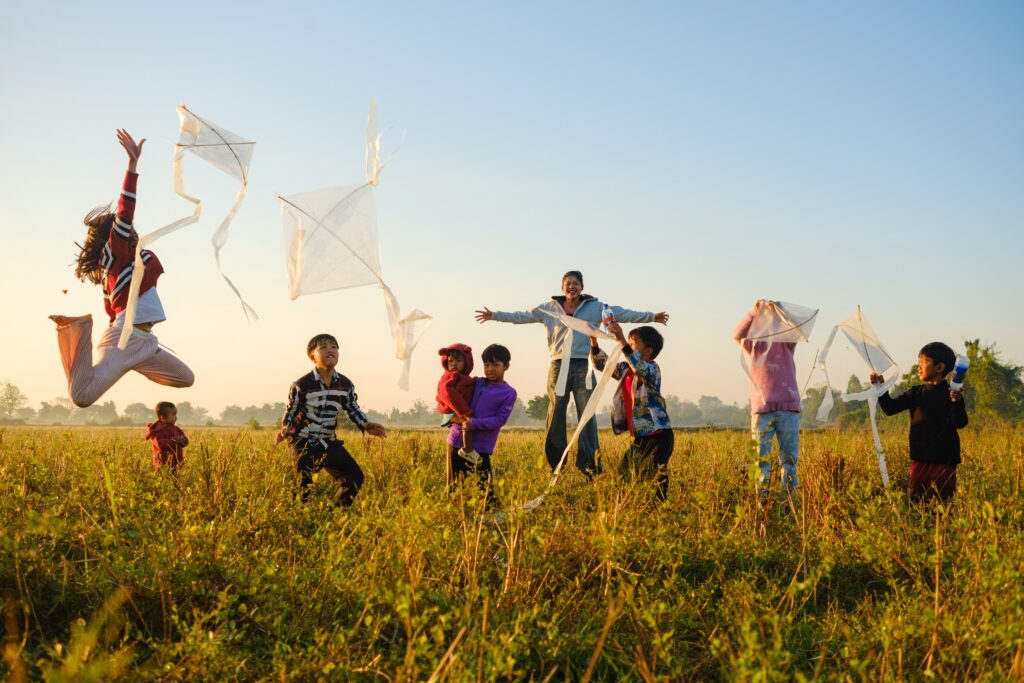 Joyful children flying kites in a Battambang field during sunrise, capturing a vibrant moment of play and freedom.
